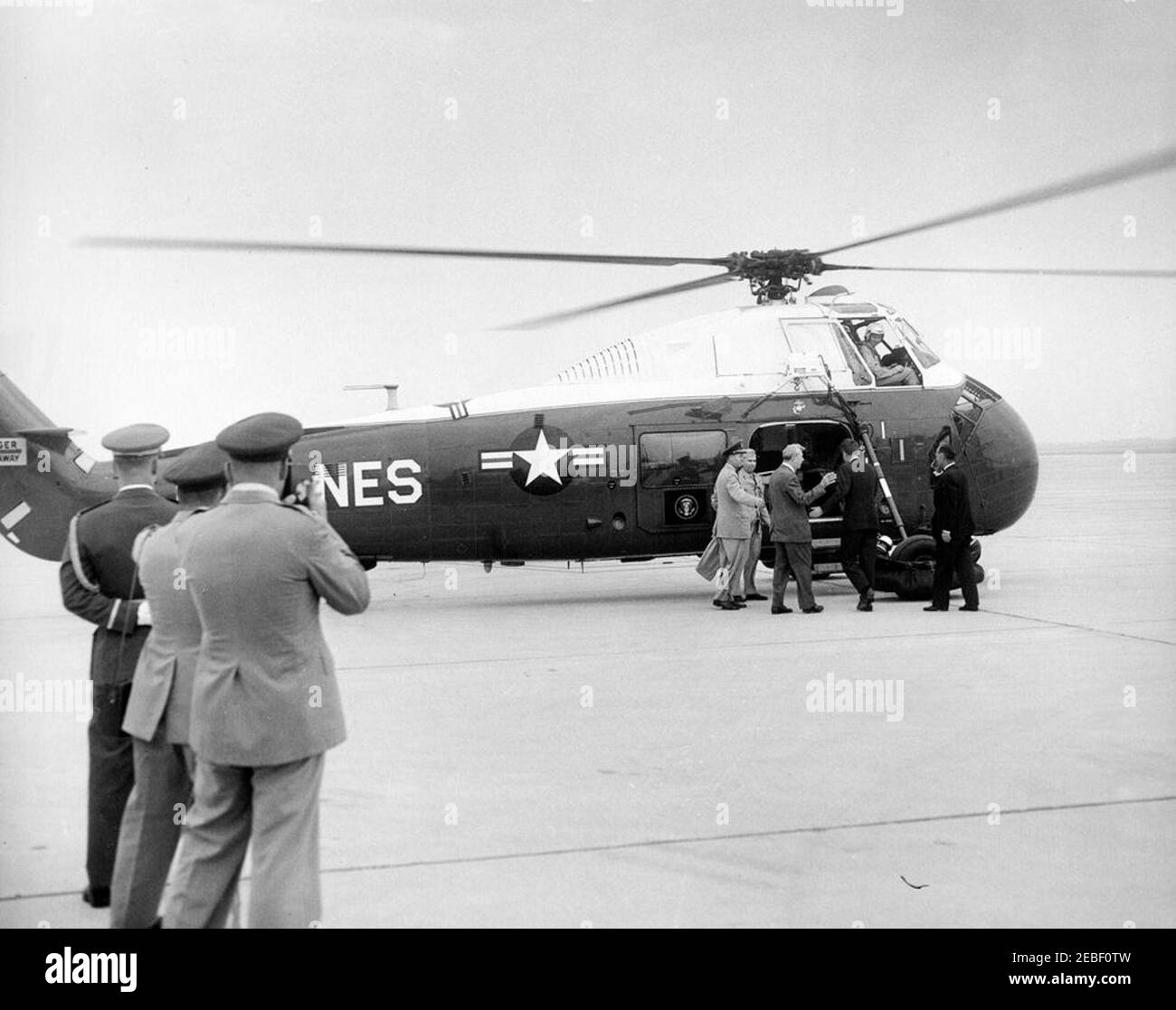 Arrival of President Kennedy at Andrews Air Force Base upon his return from Europe, 9:30AM. Arrival of President John F. Kennedy at Andrews Air Force Base in Maryland upon his return from Europe. At the United States Marine Corps helicopter (L-R): Military Aide to the President, General Chester V. Clifton; an unidentified man; Senator Everett Dirksen (Illinois); President Kennedy; an unidentified man. In the foreground are various members of the United States military. Stock Photo