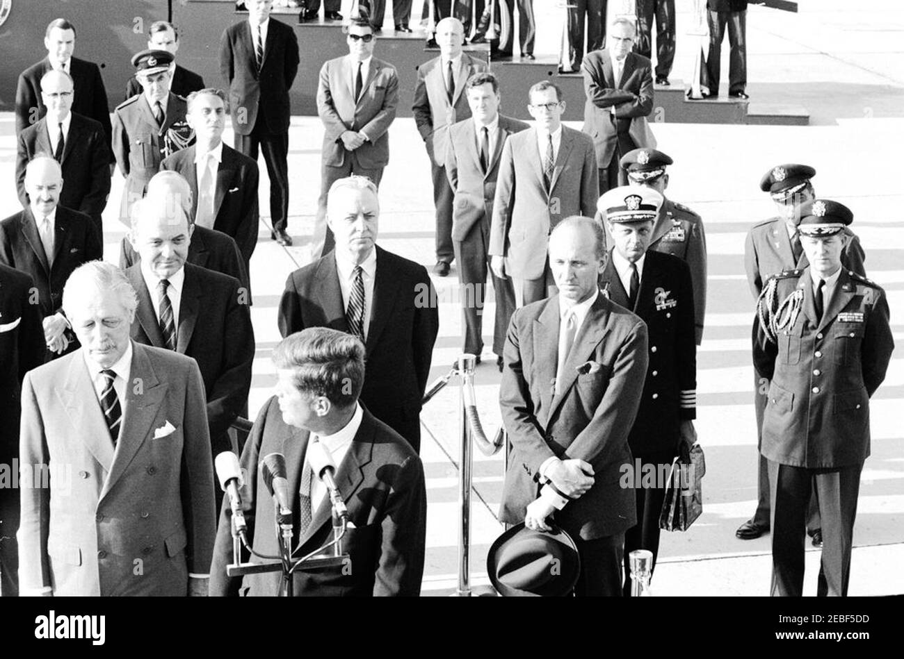 Arrival ceremonies for Harold Macmillan, Prime Minister of Great Britain, 4:50PM. President John F. Kennedy delivers welcoming remarks during arrival ceremonies in honor of Prime Minister of Great Britain, Harold Macmillan. Standing on the reviewing platform (L-R): Prime Minister Macmillan; Secretary of State, Dean Rusk; President Kennedy (at microphones, with head turned); United States Ambassador to Great Britain, David K. E. Bruce; and Chief of Protocol, Angier Biddle Duke. Also pictured: Deputy Assistant Secretary of State for European Affairs, William R. Tyler; Director of the Office of B Stock Photo