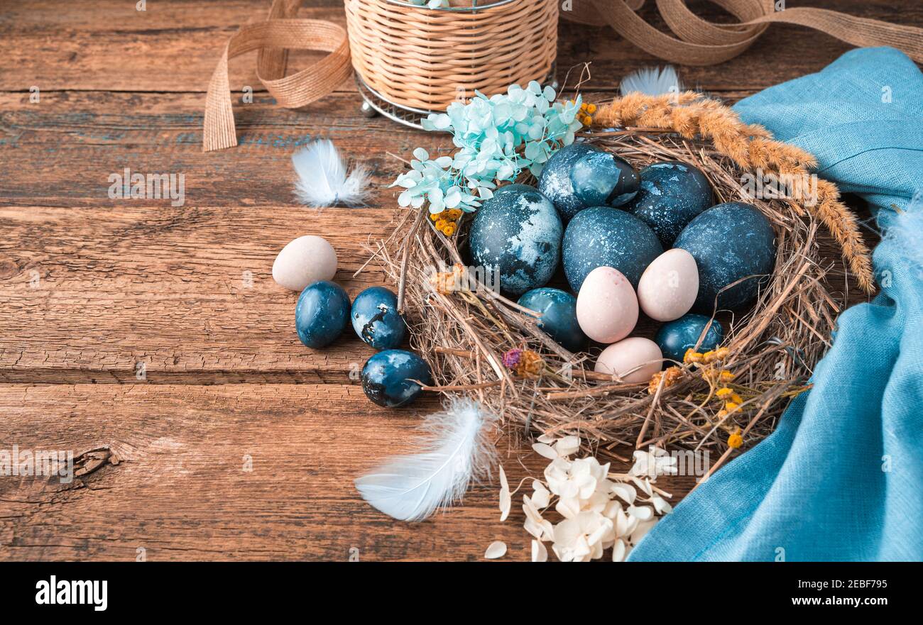 Happy Easter, festive background with eggs in a nest on a wooden background. Stock Photo