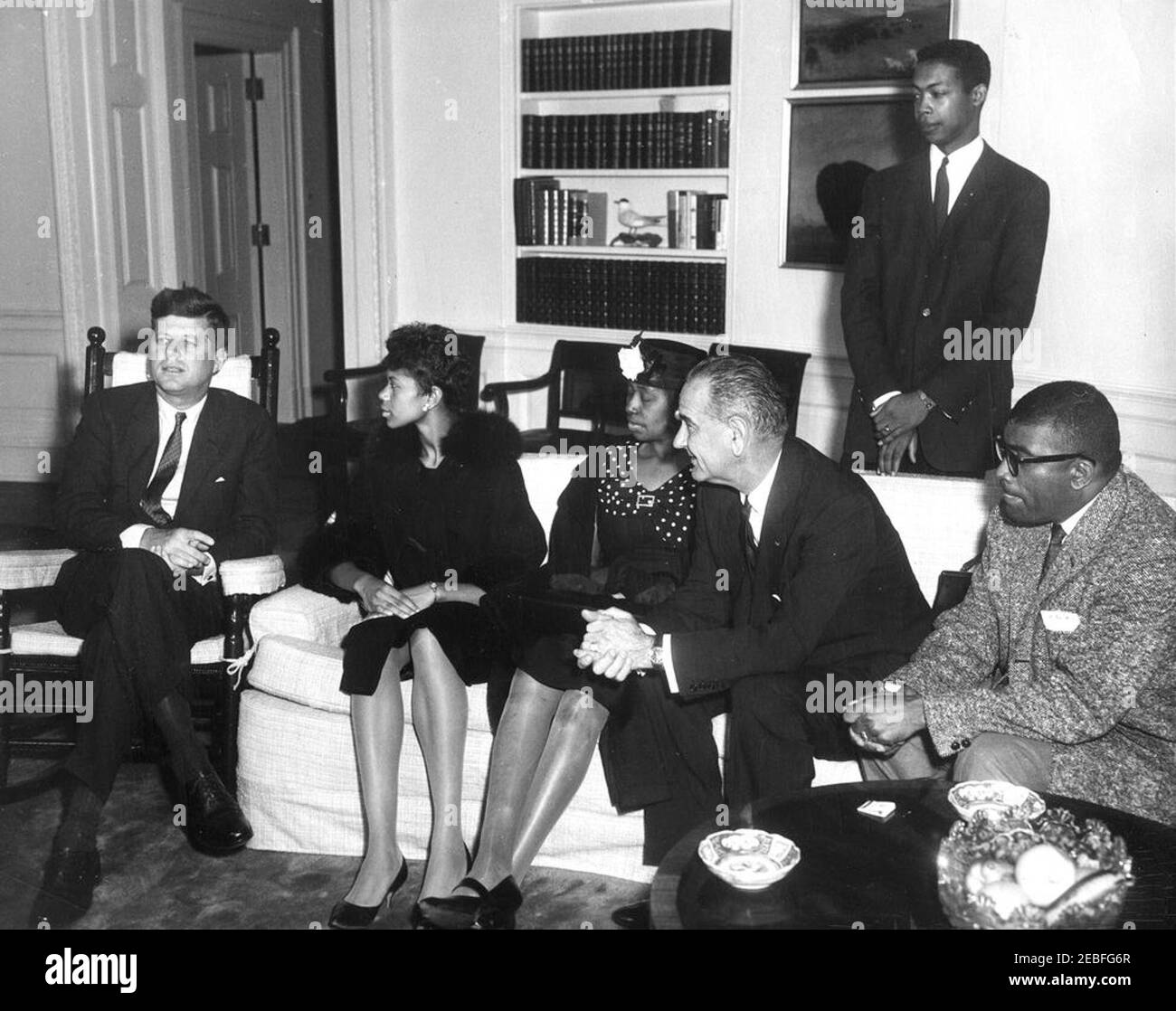 Visit of Wilma Rudolph, three-time Olympic Gold Medalist, 4:44PM. John F. Kennedy and Vice President Lyndon B. Johnson meet with Olympic track and field gold medalist Wilma Rudolph in the Oval Office, White House, Washington, D.C. (L-R) President Kennedy; Wilma Rudolph; Rudolphu2019s mother Blanche Rudolph; Vice President Johnson; Robert Logan (standing); coach of the 1960 womenu2019s Olympic track team Edward Temple. Stock Photo