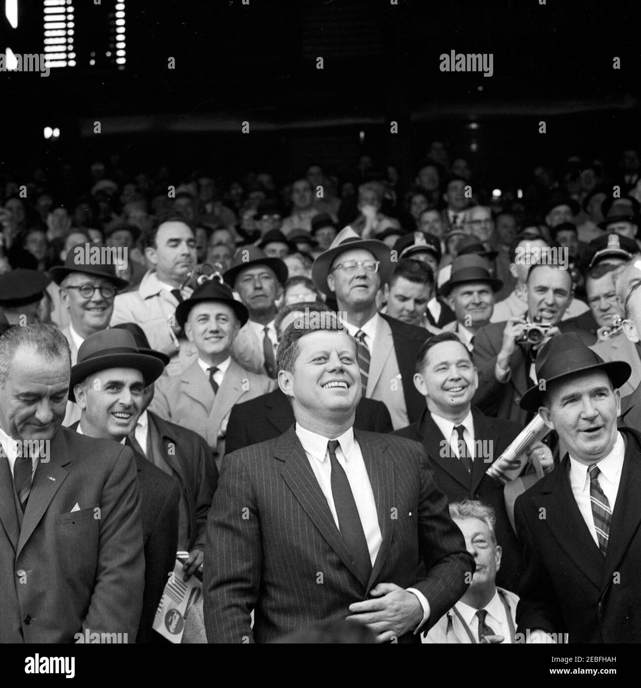 Opening Day of the 1961 Baseball Season, 1:10PM. President John F. Kennedy and others laugh during the opening game of the 1961 baseball season at Griffith Stadium, Washington, D.C. Audience includes Vice President Lyndon B. Johnson; Special Assistant to the President Dave Powers; Secretary of Health, Education, and Welfare Abraham Ribicoff; Representative Carl Albert of Oklahoma; Senate Minority Leader Everett Dirksen of Illinois. Stock Photo