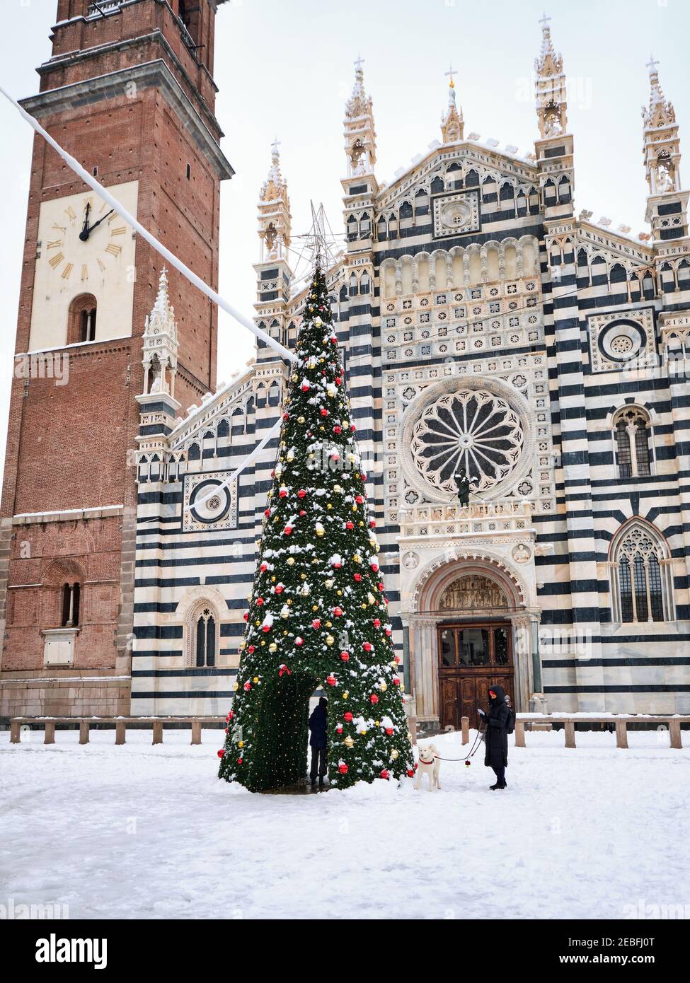 Monza Cathedral (Duomo di Monza)  covered by snow with a Christmas tree in the foreground, Italy, known as the Basilica of San Giovanni Battista. Stock Photo