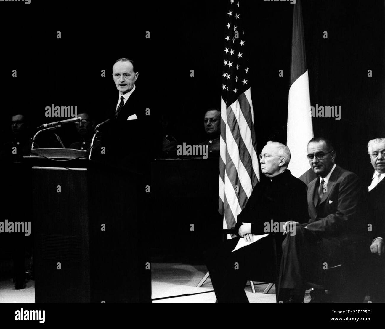 Ceremony celebrating the Unification of Italy, 10:31AM. Ceremony celebrating the Unification of Italy. L-R: Italian Ambassador to the United States, Manlio Brosio, speaks from the lectern; several unidentified members of the United States Marine Band, seated behind Brosio; Archbishop Patrick A. Ou2019Boyle, seated at right; Vice President Lyndon B. Johnson; Congressman Roland V. Libonati (Illinois). State Department Auditorium, Washington, D.C.rnrn Stock Photo