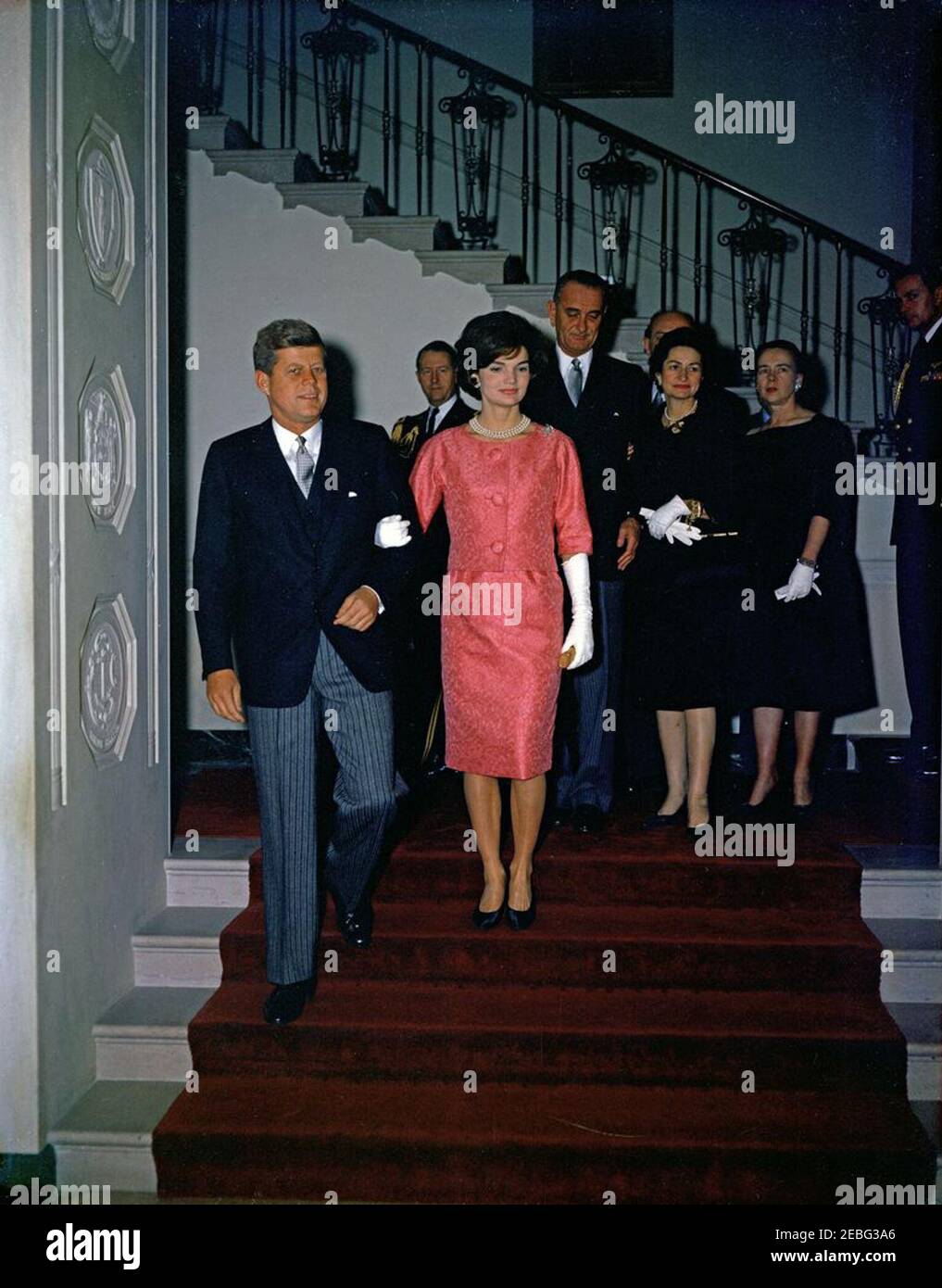 Reception for members of the Diplomatic Corps, 5:00PM. Reception for members of the Diplomatic Corps, White House, Washington, D.C. President John F. Kennedy and First Lady Jacqueline Kennedy descend the Grand Staircase to the Entrance Hall. Behind them (L-R) are Military Aide to the President Chester V. Clifton; Vice President Lyndon B. Johnson; Secretary of State Dean Rusk (partially hidden); Lady Bird Johnson; Dean Rusku0027s wife Virginia Rusk; Naval Aide to the President Tazewell Shepard, Jr. Stock Photo
