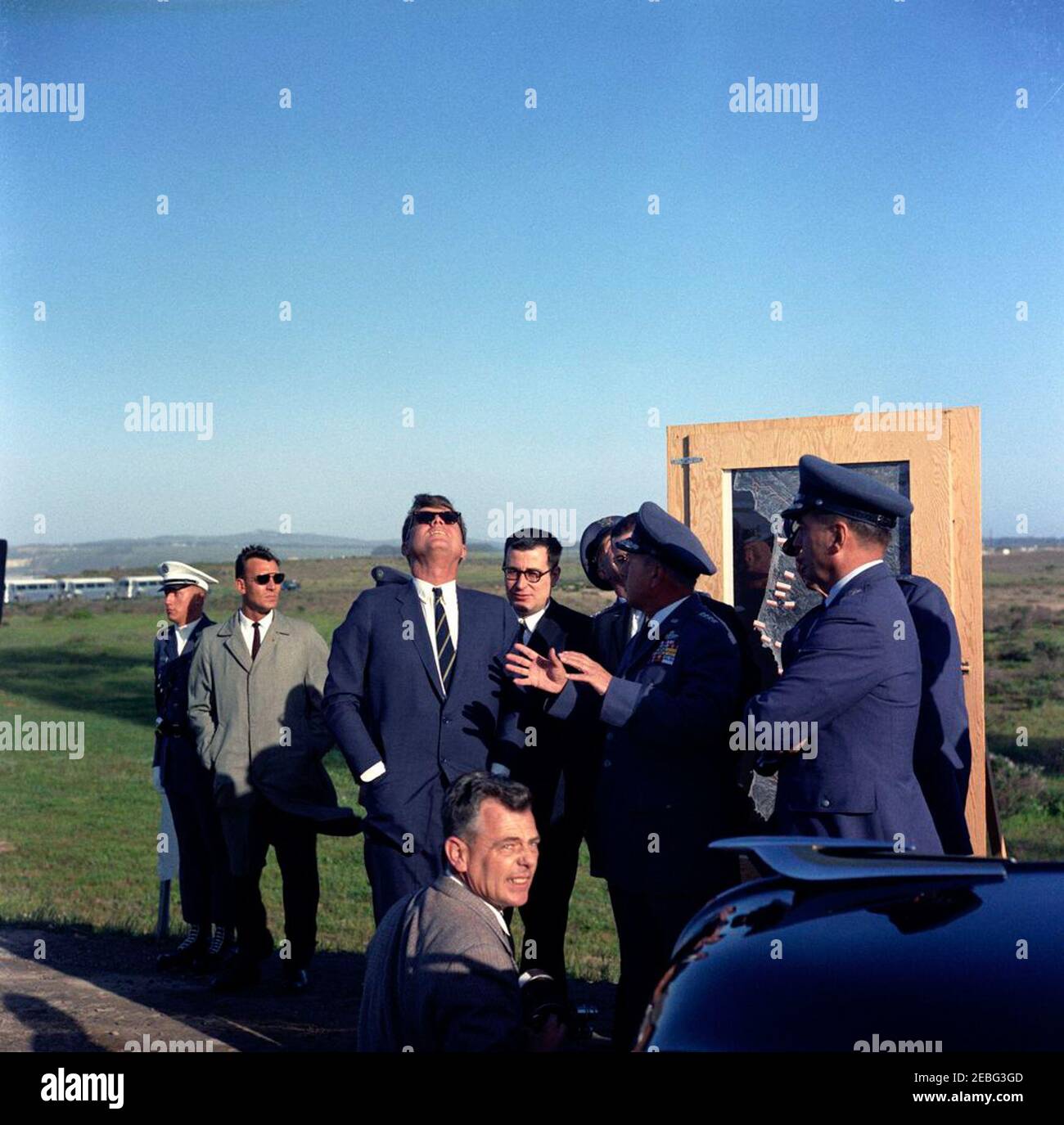 Trip to California: Vandenberg Air Force Base, 4:08PM. President John F. Kennedy (wearing sunglasses) watches Atlas 134D missile launch at Vandenberg Air Force Base, California. Left to right: Unidentified man; White House Secret Service agent, Bob Lilley; President Kennedy; Director of Research and Development for the Department of Defense, Dr. Harold Brown; Commander of Strategic Air Command, General Thomas S. Power; Air Force Aide to the President, Brigadier General Godfrey T. McHugh. An unidentified photographer stands in foreground. Stock Photo