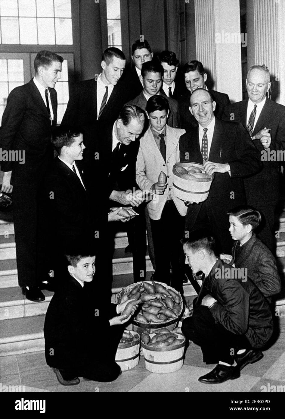 A 4-H Club visits the White House. Special Assistant to the President Dave Powers (holding basket) poses with Senator Olin Johnston of South Carolina (bending over); the champion 4-H Club sweet potato growers for the State of South Carolina for 1960; and their gift of sweet potatoes at the White House, Washington, D. C. 4-H Club members include: Dan Bates; Gene Ousley; Junior Boykin; Mack Ousley; Dwight Lee; Kenneth Cooper; Paul Linwood Shuler; Carson Blackwell; Donald Bagnall; Henry David Gunter; Ernest Boykin. The man right of Dave Powers is unidentified.rn Stock Photo