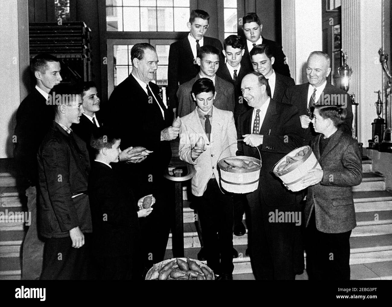 A 4-H Club visits the White House. Special Assistant to the President Dave Powers (holding basket) poses with Senator Olin Johnston of South Carolina (holding sweet potato); the champion 4-H Club sweet potato growers for the State of South Carolina for 1960; and their gift of sweet potatoes at the White House, Washington, D. C. 4-H Club members include: Dan Bates; Gene Ousley; Junior Boykin; Mack Ousley; Dwight Lee; Kenneth Cooper; Paul Linwood Shuler; Carson Blackwell; Donald Bagnall; Henry David Gunter; Ernest Boykin. The man right of Dave Powers is unidentified.rn Stock Photo