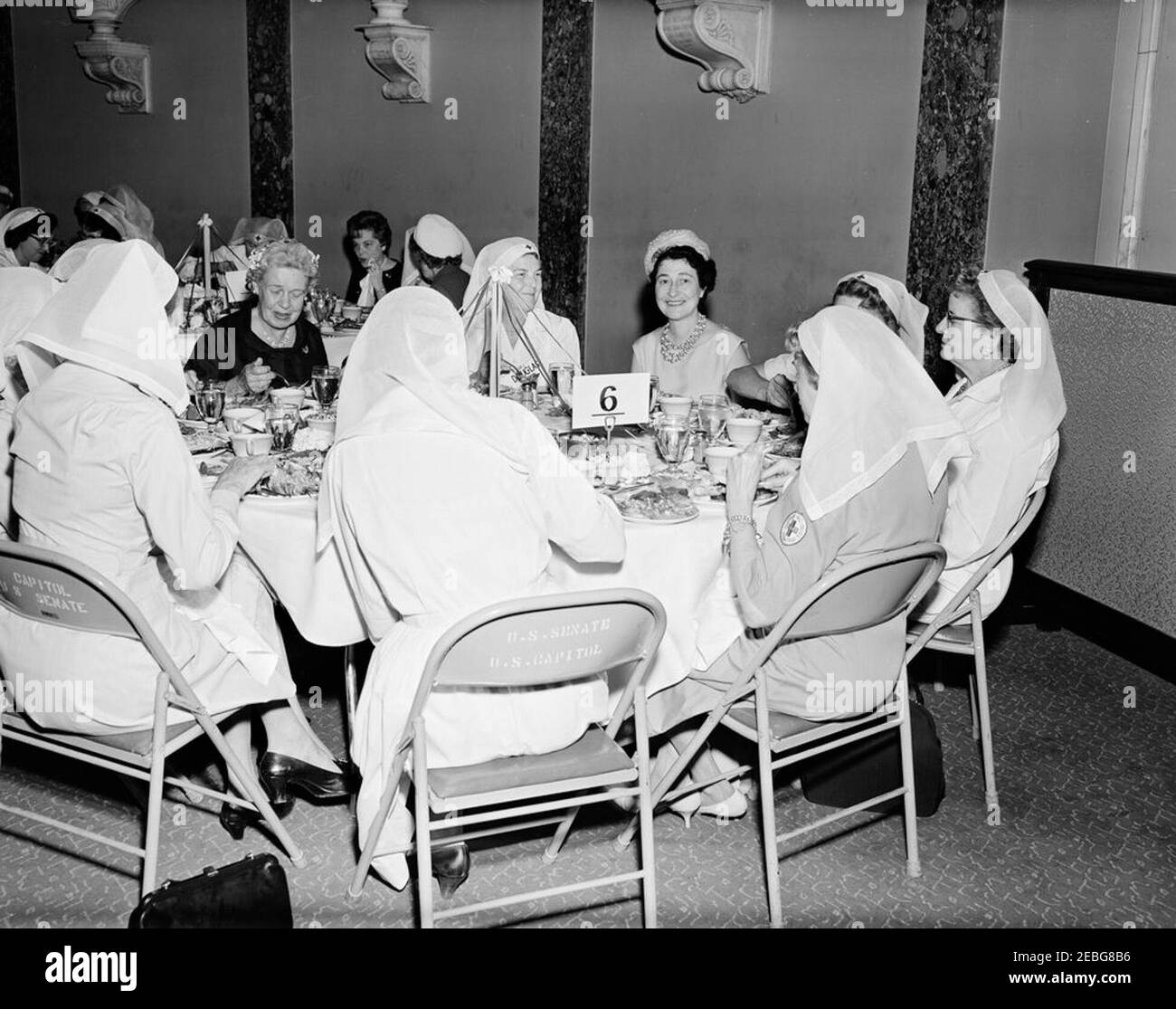 First Lady Jacqueline Kennedy (JBK) attends the Senate Ladiesu0027 Red Cross Unit Luncheon. Members of the Senate Ladies Red Cross Unit sit at a table during a luncheon (attended by First Lady Jacqueline Kennedy) in the Old Supreme Court Chamber, United States Capitol Building, Washington, D.C. The Red Cross unit (also known as u201cLadies of the Senateu201d) is comprised of the wives of members of the US Senate. Seated at center left is Emily Douglas, former Representative from Illinois and wife of Senator Paul H. Douglas (Illinois); all others are unidentified. Stock Photo