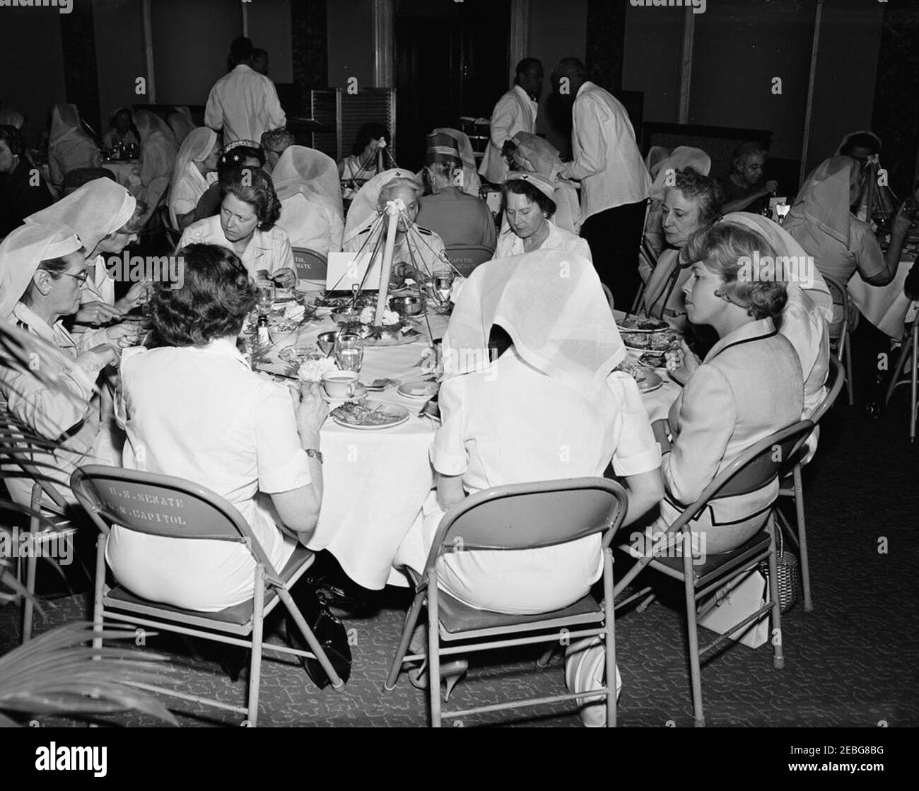 First Lady Jacqueline Kennedy (JBK) attends the Senate Ladiesu0027 Red Cross Unit Luncheon. Members of the Senate Ladies Red Cross Unit sit at a table during a luncheon (attended by First Lady Jacqueline Kennedy) in the Old Supreme Court Chamber, United States Capitol Building, Washington, D.C. The Red Cross unit (also known as u201cLadies of the Senateu201d) is comprised of the wives of members of the US Senate. Those seated at table in foreground include: Mary Elizabeth Kem, wife of former Senator James Kem (Missouri); Lucretia Engle (back to camera), wife of Senator Clair Engle (Californ Stock Photo
