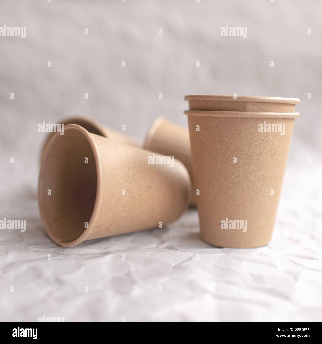 disposable kraft paper cups laid out on gray crumpled paper in geometric pattern Stock Photo