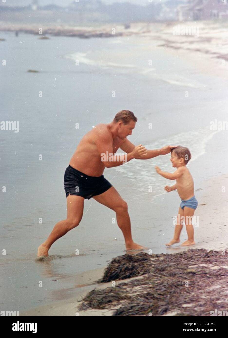 Labor Day Weekend at Hyannis Port: Caroline Kennedy (CBK), John F. Kennedy, Jr. (JFK Jr.), Maud Shaw, and John u0022Sandyu0022 Eiler on beach. John F. Kennedy, Jr., plays with Kennedy family athletic instructor, Sandy Eiler, on a beach during Labor Day weekend in Hyannis Port, Massachusetts. Stock Photo