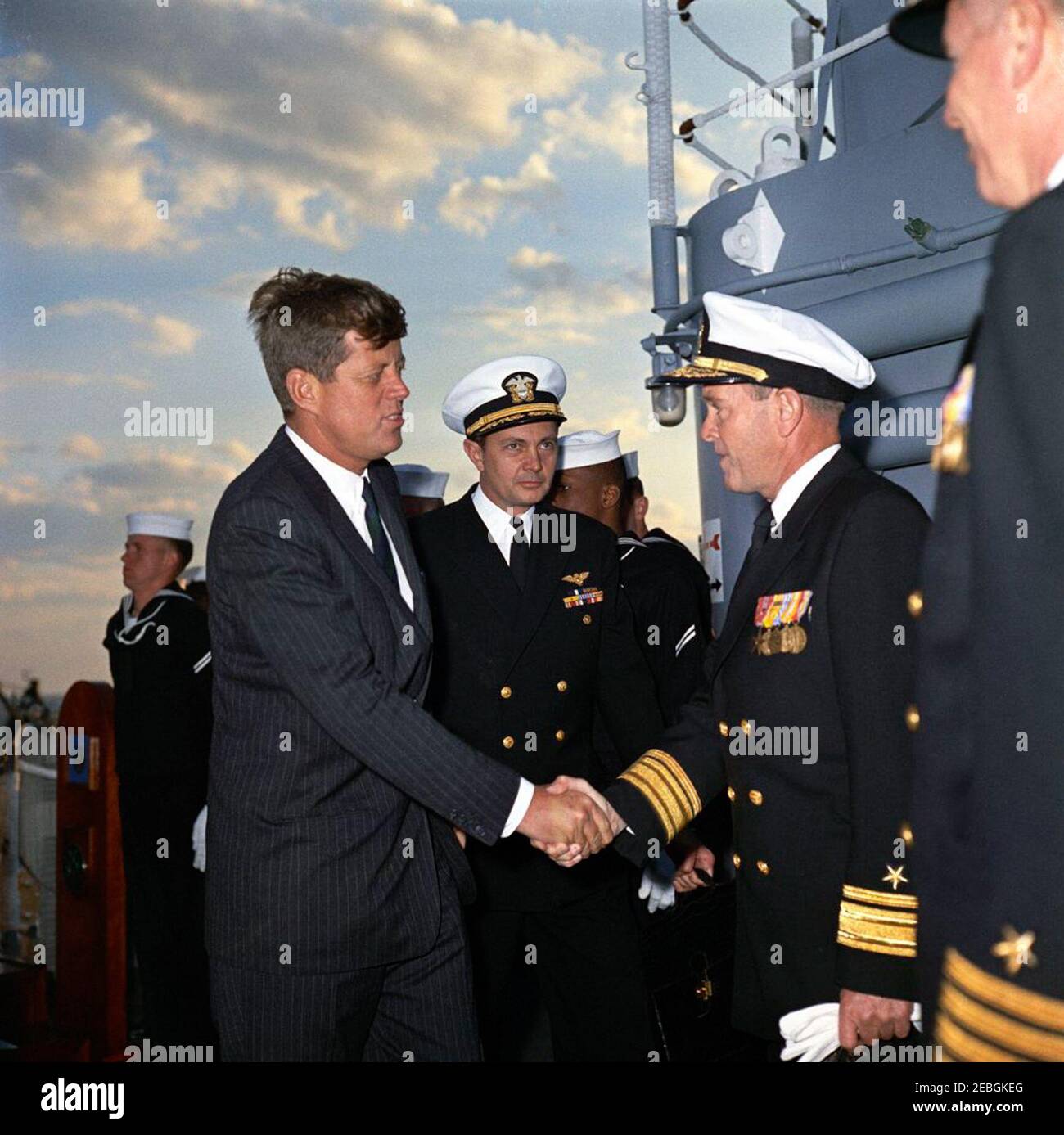 Visit to the Atlantic Fleet: President Kennedy greets SEALs, boards USS Northampton (CC-1), 5:20PM. President John F. Kennedy greets an unidentified United States Navy rear admiral upon boarding the cruiser USS Northampton (CC-1), command ship of the U.S. Atlantic Fleet, dockside at Naval Air Station, Norfolk, Virginia. Naval Aide to the President Captain Tazewell Shepard, Jr. (back center) stands behind President Kennedy. The President boarded the ship for an overnight cruise to view fleet exercises. Stock Photo