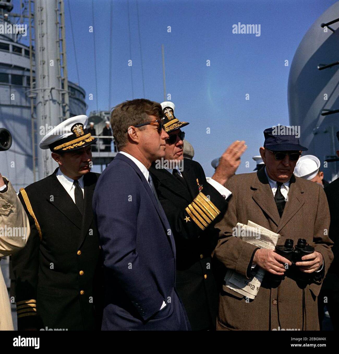 Visit to the Atlantic Fleet: President Kennedy aboard USS Northampton (CC-1). An unidentified United States Navy admiral (center right, gesturing with his right hand) briefs President John F. Kennedy (wearing sunglasses) during a review of the U.S. Atlantic Fleet from the deck of the command cruiser USS Northampton (CC-1), at sea off the coast of Virginia and North Carolina. Naval Aide to the President Captain Tazewell Shepard, Jr. (second from left) and Senator Richard B. Russell of Georgia (far right, holding binoculars) look on. Stock Photo