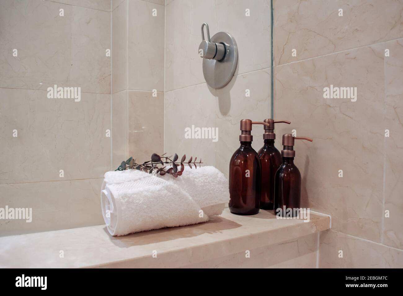 Amber glass shampoo bottles with copper steel pump dispensers in a luxury marble hotel spa and shower. Stock Photo