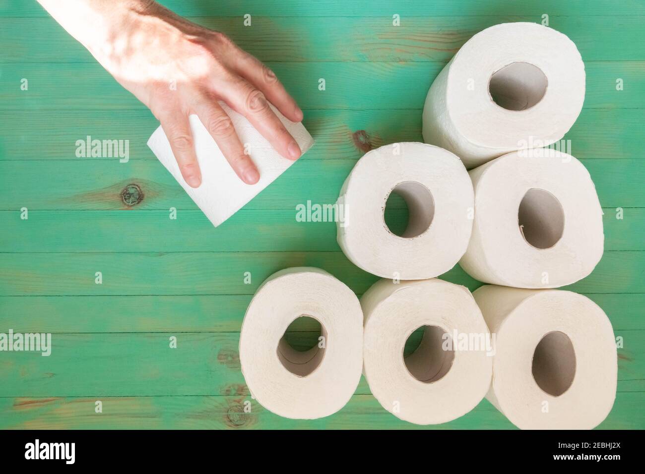 Senior hand outstretched to take toilet paper roll from. Toilet paper rolls hoarding at home of hoarder amidst panic buying for coronavirus outbreak s Stock Photo