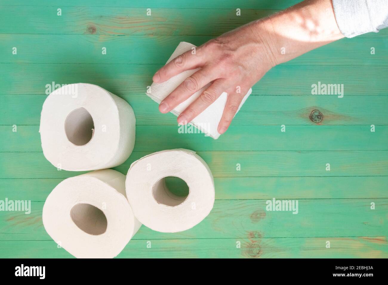Senior hand outstretched to take toilet paper roll. People panic buying toilet paper rolls for coronavirus outbreak shortage. Stock Photo