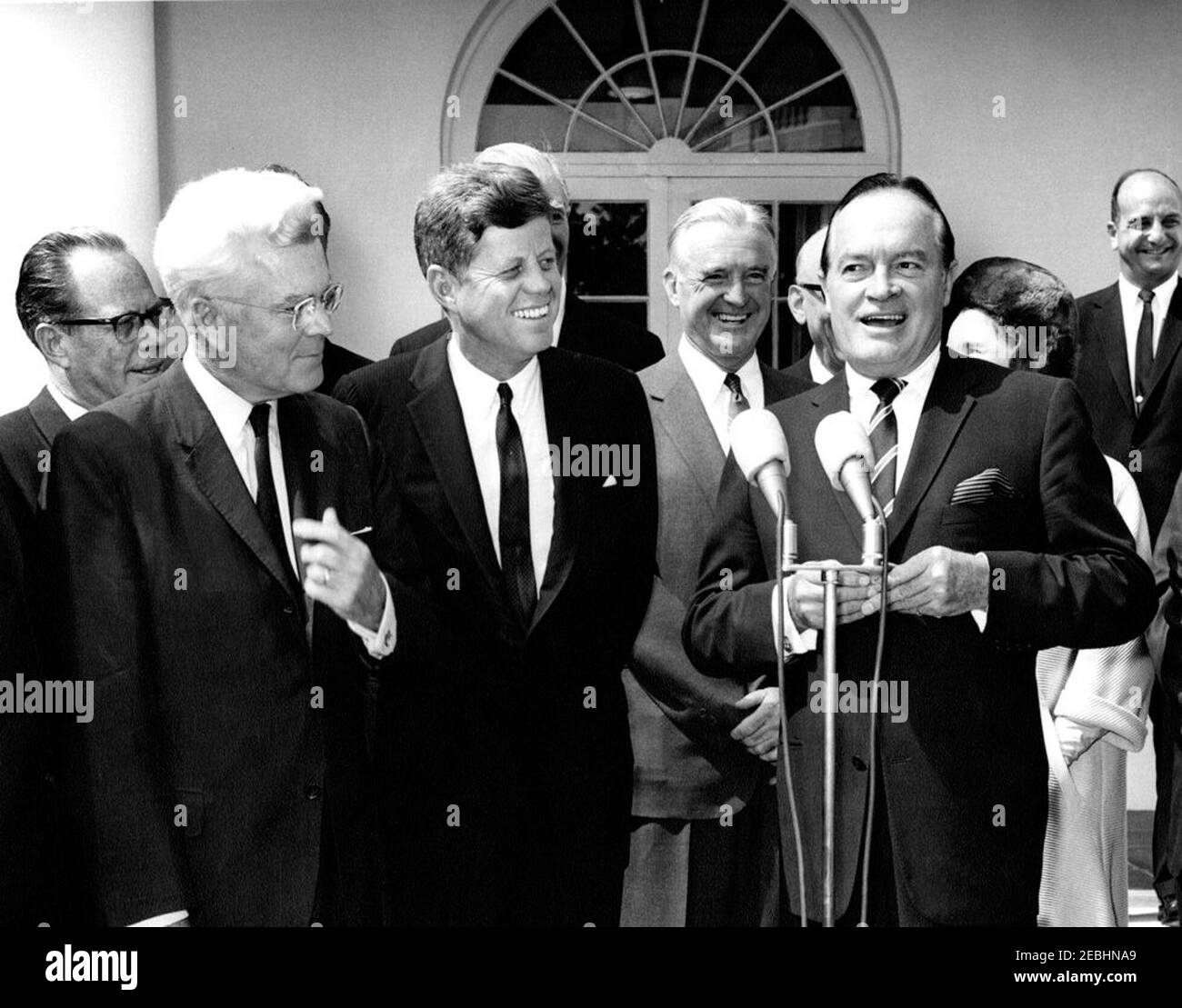 Presentation of a Congressional Gold Medal to Bob Hope, 12:10PM. President John F. Kennedy laughs as actor and comedian, Bob Hope, delivers remarks after receiving the Congressional Gold Medal, presented by President Kennedy in recognition of his services to the country as an entertainer during World War II. Left to right: Senator Thomas H. Kuchel (California); Representative Michael A. Feighan (Ohio); President Kennedy; Senator Stuart Symington (Missouri); Mr. Hope; Dolores Hope (mostly hidden), wife of Mr. Hope; unidentified man. Rose Garden, White House, Washington, D.C. Stock Photo