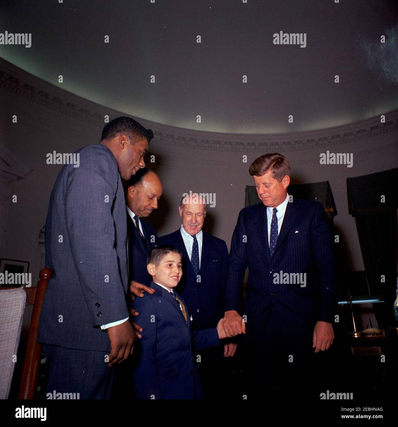 Visit of members of the Big Brothers Association, including Heavyweight Boxing Champion Floyd Patterson, 12:25PM. President John F. Kennedy greets representatives of the Big Brothers Association in connection with Big Brothers Week. The President holds the hand of ten-year-old Freddie Cicala, a u201clittle brotheru201d member of the Big Brothers organization. Looking on are (L-R): World heavyweight boxing champion Floyd Patterson; John Duncan, member of the District of Columbia Board of Commissioners; and journalist Drew Pearson. Oval Office, White House, Washington, D.C. Stock Photo