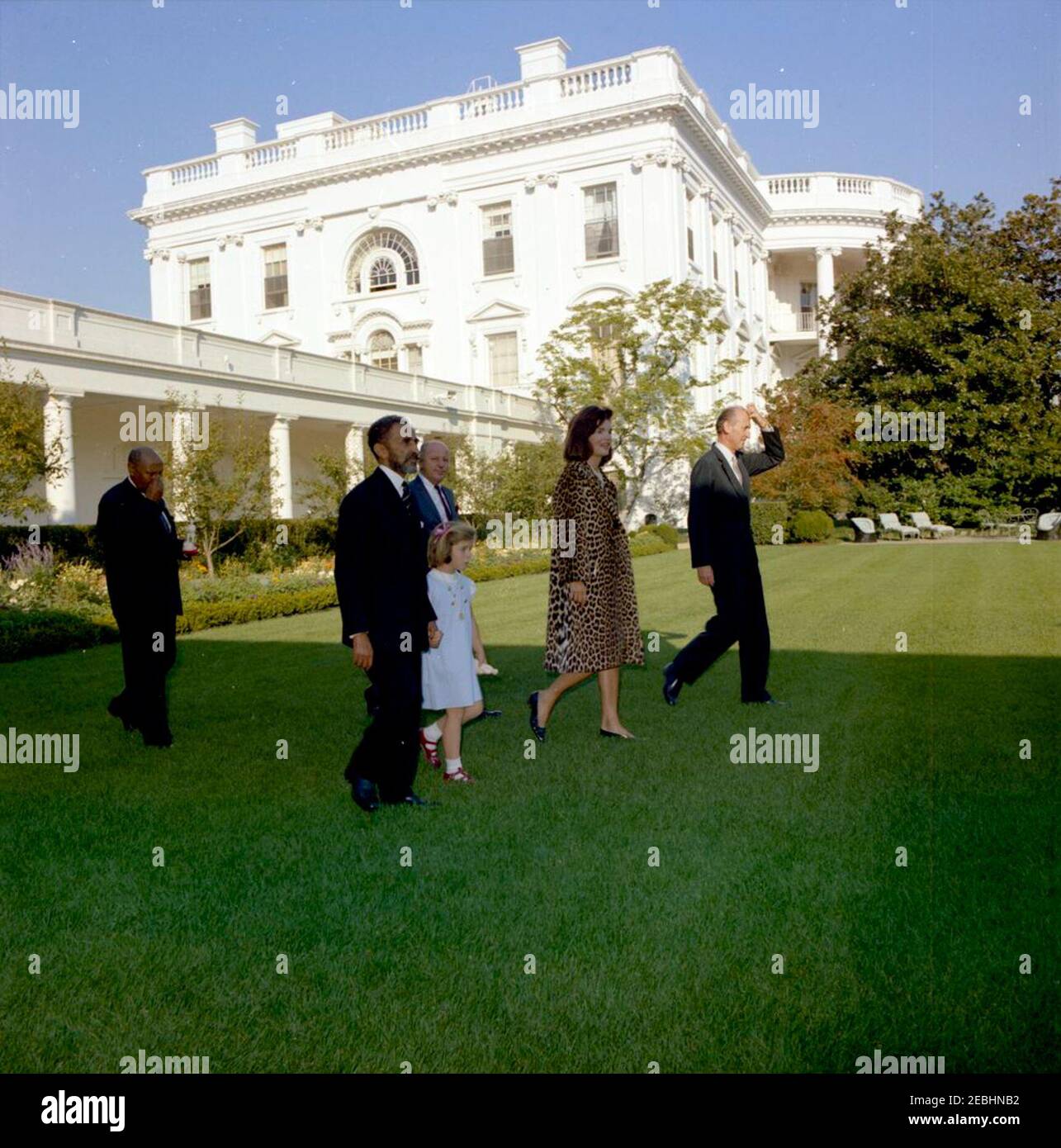 Meeting with Haile Selassie I, Emperor of Ethiopia, 4:33PM. First Lady Jacqueline Kennedy walks with Emperor of Ethiopia, Haile Selassie I, through the Rose Garden of the White House. Left to right: Minister of the Imperial Court of Ethiopia, Tafarra-Worq Kidane-Wold; Emperor Selassie; Caroline Kennedy; U.S. State Department Protocol officer, Jay Rutherfurd (behind); Mrs. Kennedy; U.S. Chief of Protocol, Angier Biddle Duke. The Emperor presented as gifts to the Kennedy family a leopard coat and gold filigree jewelry case for the First Lady and carved ivory figurines for Caroline and John F. Ke Stock Photo