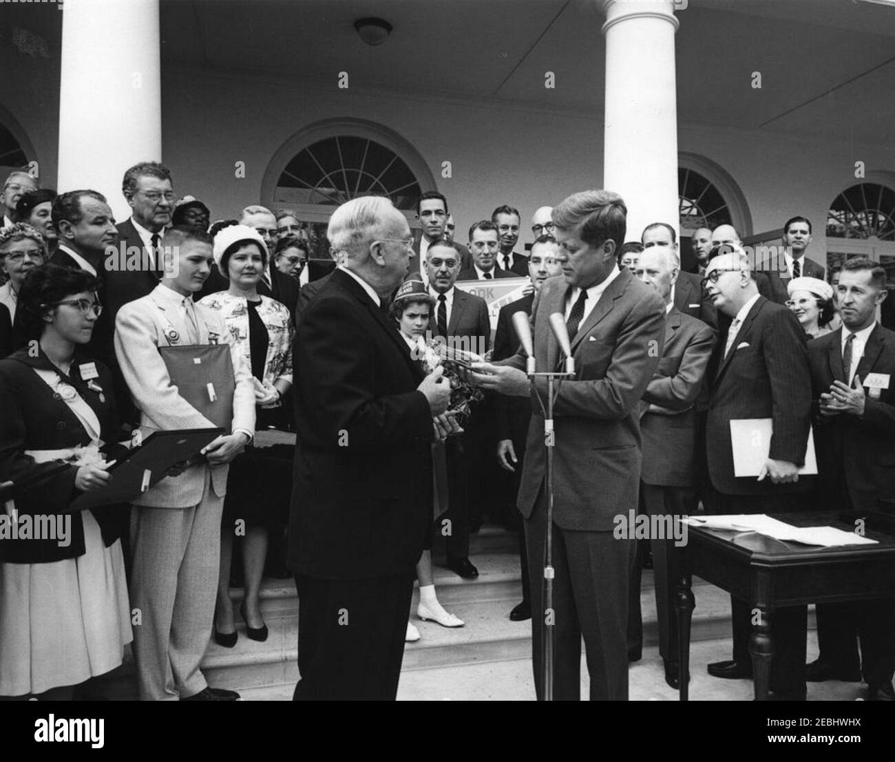 Presentation of the American Automobile Association (AAA) Lifesaving Awards in the Rose Garden, 9:50AM. President John F. Kennedy (center) receives a gift of an American Automobile Association (AAA) medal from President of the AAA Traffic Safety Foundation, Judge Clarence E. Bodie, during the AAA Lifesaving Awards ceremony; five members of the organizationu2019s School Safety Patrol received the award. Those pictured include: award recipients Patricia Miller (of Hereford, Pennsylvania) and Wesley Haines (of Dayton, Ohio); Senator George A. Smathers (Florida); Representative Paul F. Schenck (O Stock Photo