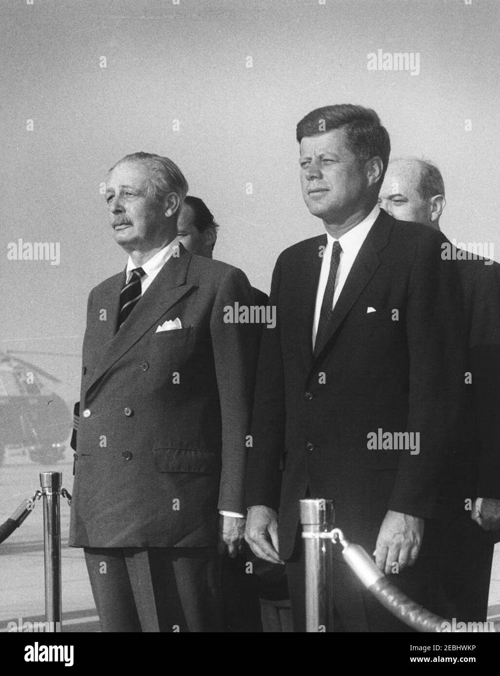 Arrival ceremonies for Harold Macmillan, Prime Minister of Great Britain, 4:50PM. President John F. Kennedy attends arrival ceremonies in honor of Prime Minister of Great Britain, Harold Macmillan. Left to right: Prime Minister Macmillan; Ambassador of Great Britain, Sir David Ormsby-Gore (in back, mostly hidden); President Kennedy; and Secretary of State, Dean Rusk (in back, mostly hidden). Andrews Air Force Base, Maryland. Stock Photo