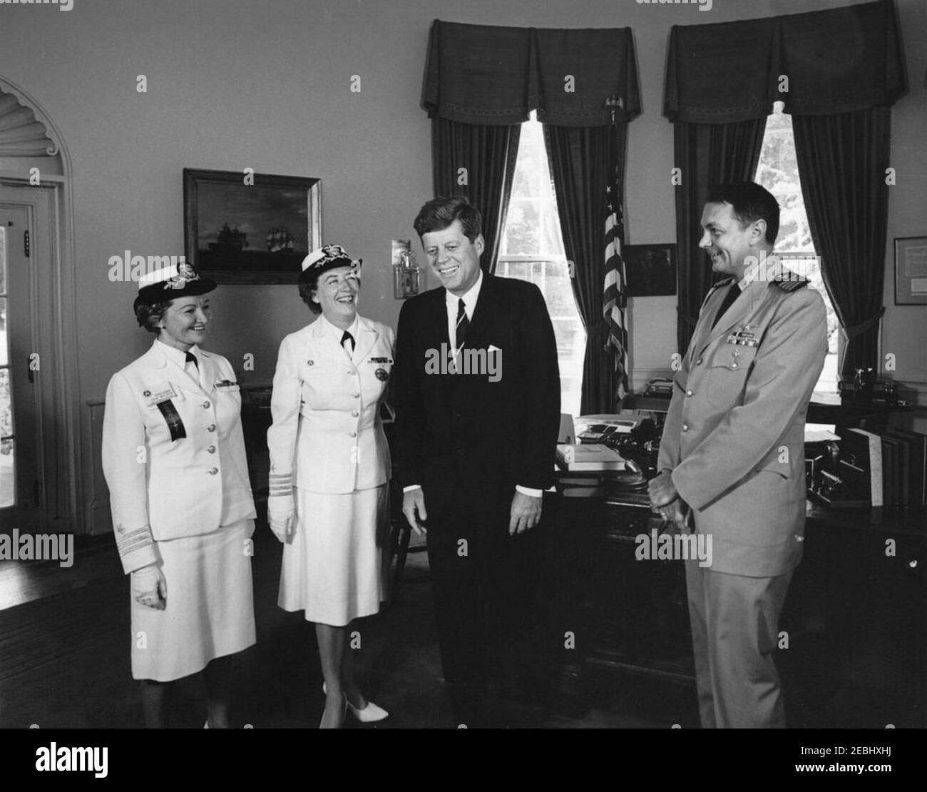 Visit of Captain Winifred Quick Collins, Director of Women Accepted for Volunteer Emergency Service (WAVES), 9:48AM. President John F. Kennedy visits with U.S. Navy officers. Left to right: Women Accepted for Volunteer Emergency Service (WAVES) officer, Captain Irene Wolensky; Director of WAVES, Captain Winifred Quick Collins; President Kennedy; and Naval Aide to the President, Captain Tazewell T. Shepard, Jr. Oval Office, White House, Washington, D.C. Stock Photo