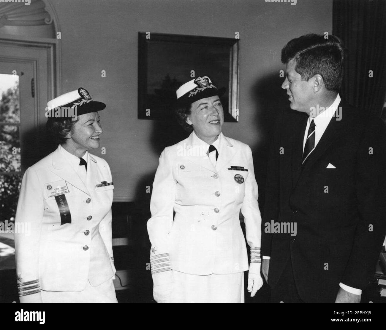 Visit of Captain Winifred Quick Collins, Director of Women Accepted for Volunteer Emergency Service (WAVES), 9:48AM. President John F. Kennedy visits with U.S. Navy officers. Left to right: Women Accepted for Volunteer Emergency Service (WAVES) officer, Commander Irene Wolensky; Director of WAVES, Captain Winifred Quick Collins; and President Kennedy. Oval Office, White House, Washington, D.C. Stock Photo