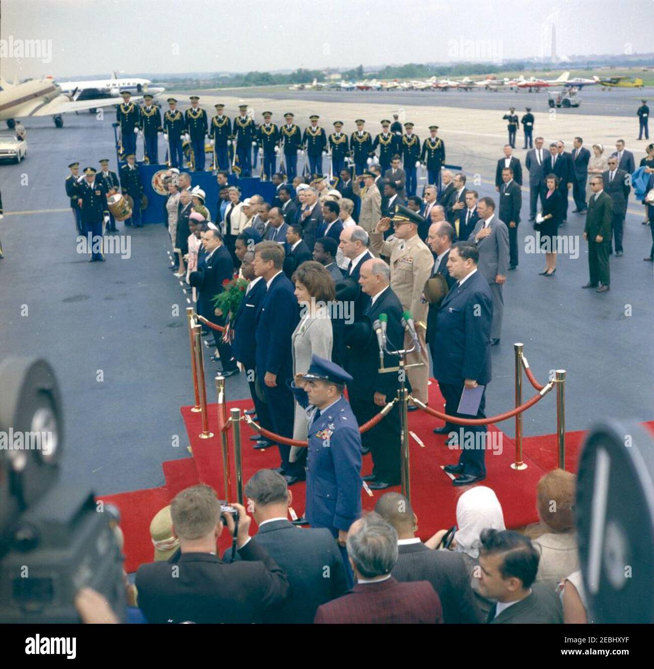 Arrival ceremony for Fu00e9lix Houphouu00ebt-Boigny, President of the Ivory Coast, 12:00PM. President John F. Kennedy, First Lady Jacqueline Kennedy, and others attend arrival ceremonies in honor of President of the Ivory Coast, Fu00e9lix Houphouu00ebt-Boigny. Standing on platform: President Kennedy; Mrs. Kennedy; President Houphouu00ebt-Boigny; First Lady of the Ivory Coast, Marie-Thu00e9ru00e8se Houphouu00ebt-Boigny; Ambassador of the Ivory Coast, Henri Konan Bu00e9diu00e9; U.S. Secretary of State, Dean Rusk; U.S. Ambassador to the Ivory Coast, R. Borden Reams; Vice Chief of Staff Stock Photo