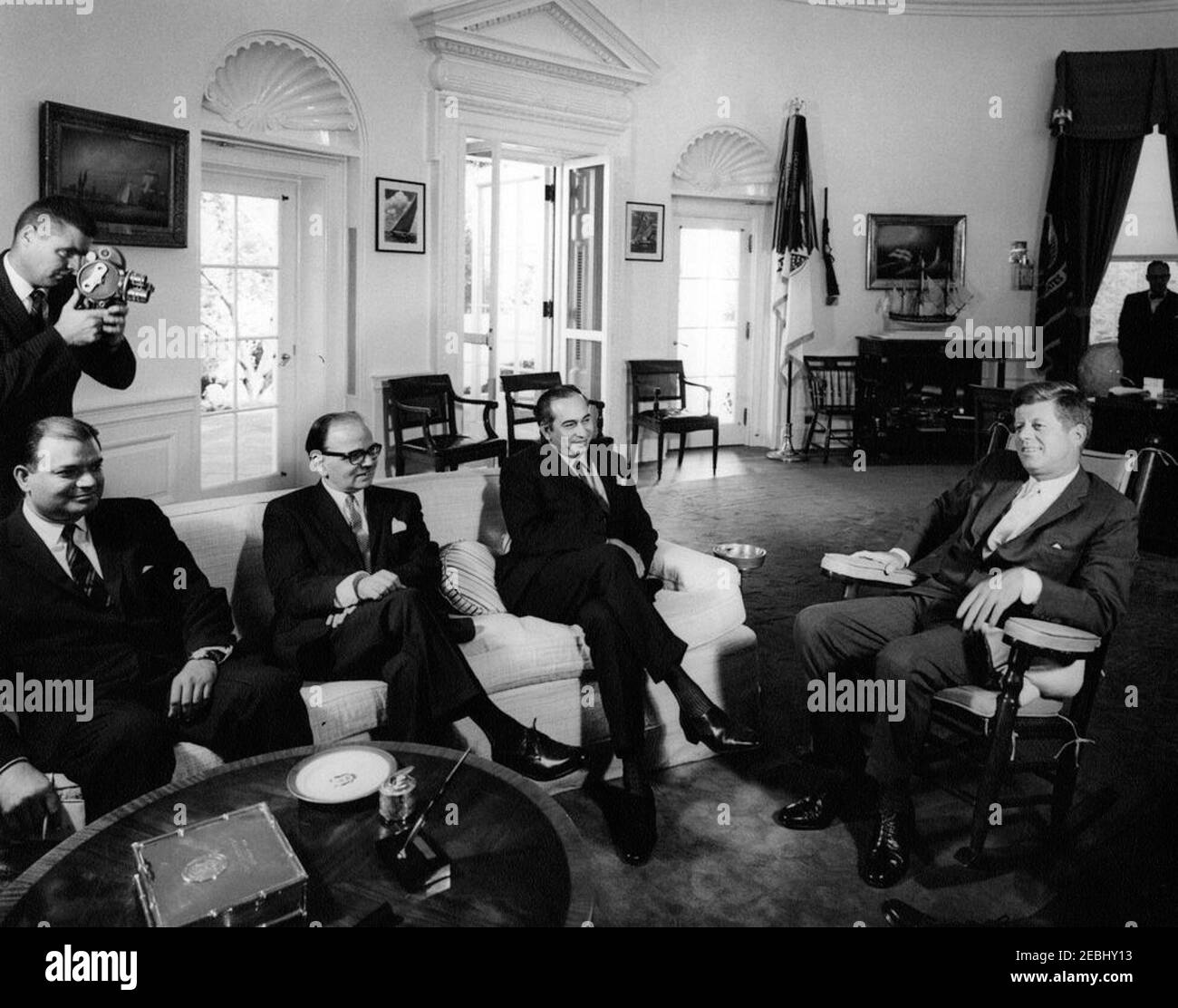 Meeting with Zulfiqar Ali Bhutto, Foreign Minister of Pakistan, 4:00PM. President John F. Kennedy (in rocking chair) meets with Foreign Minister of Pakistan, Zulfikar (Zulfiqar) Ali Bhutto. Seated (L-R): First Secretary of the Embassy of Pakistan, Mujahid Ali Jafri; Ambassador of Pakistan, Ghulam Ahmed; Minister Bhutto; and President Kennedy. An unidentified photographer stands at far left. Oval Office, White House, Washington, D.C. Stock Photo