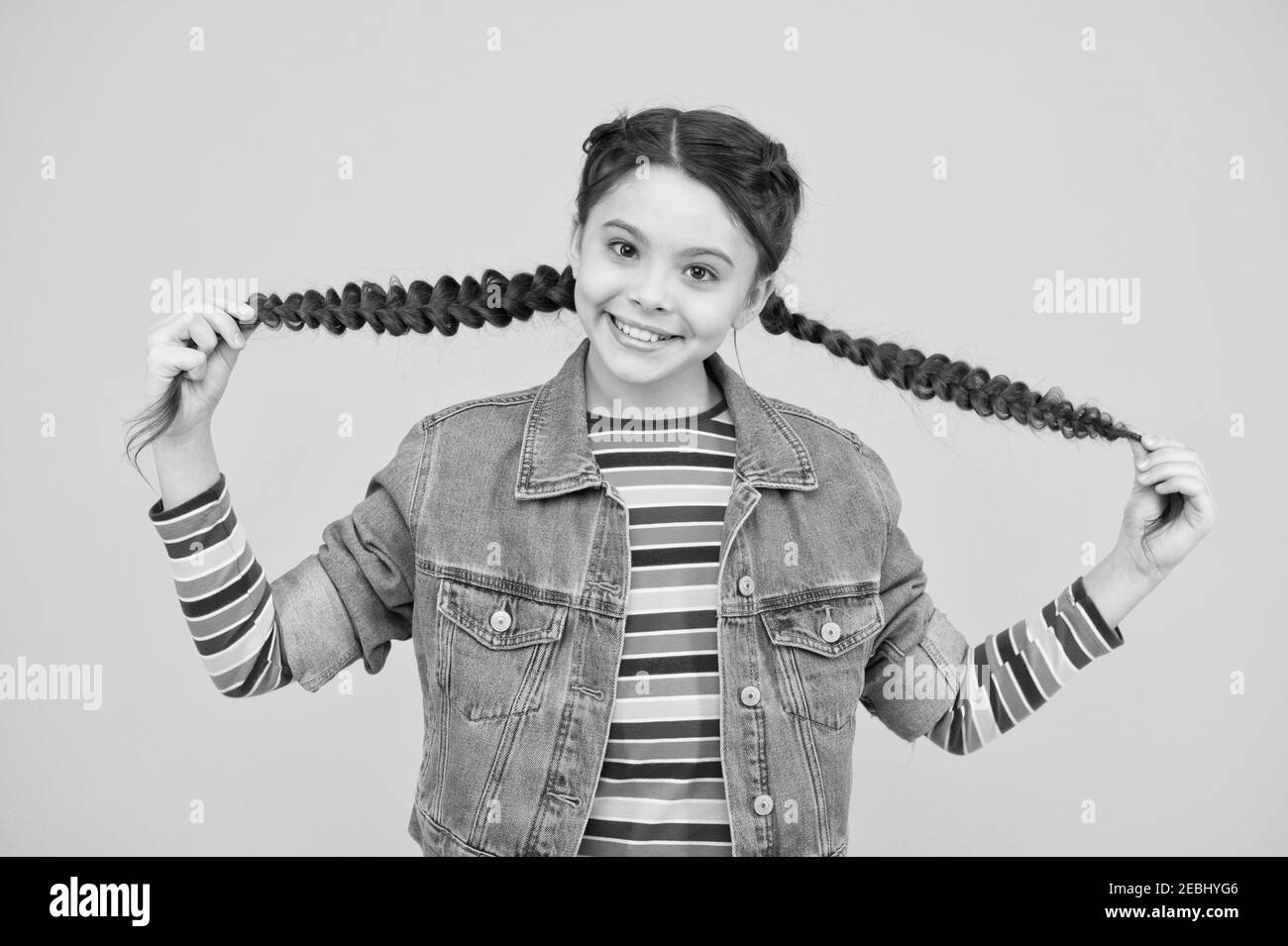 Happy little girl with braids wear denim clothes, kids clothes concept. Stock Photo