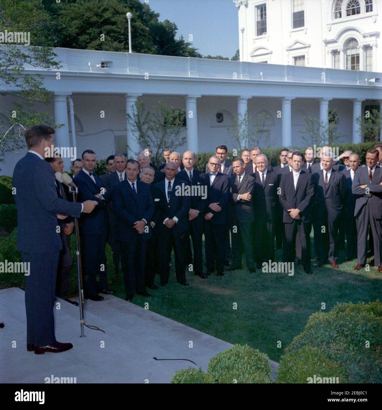 Visit of Directors u0026 Deputy Directors of various Agency for International Development (AID) Missions, 4:45PM. President John F. Kennedy delivers remarks to a group of directors and deputy directors of Agency for International Development (AID) missions. Director of the mission in Yemen, James Megellas, stands four right of President Kennedy (in back). Also pictured: White House Secret Service agent, Bob Lilley. Rose Garden, White House, Washington, D.C. [Please see the Presidentu2019s schedule for a complete list of attendees.] Stock Photo