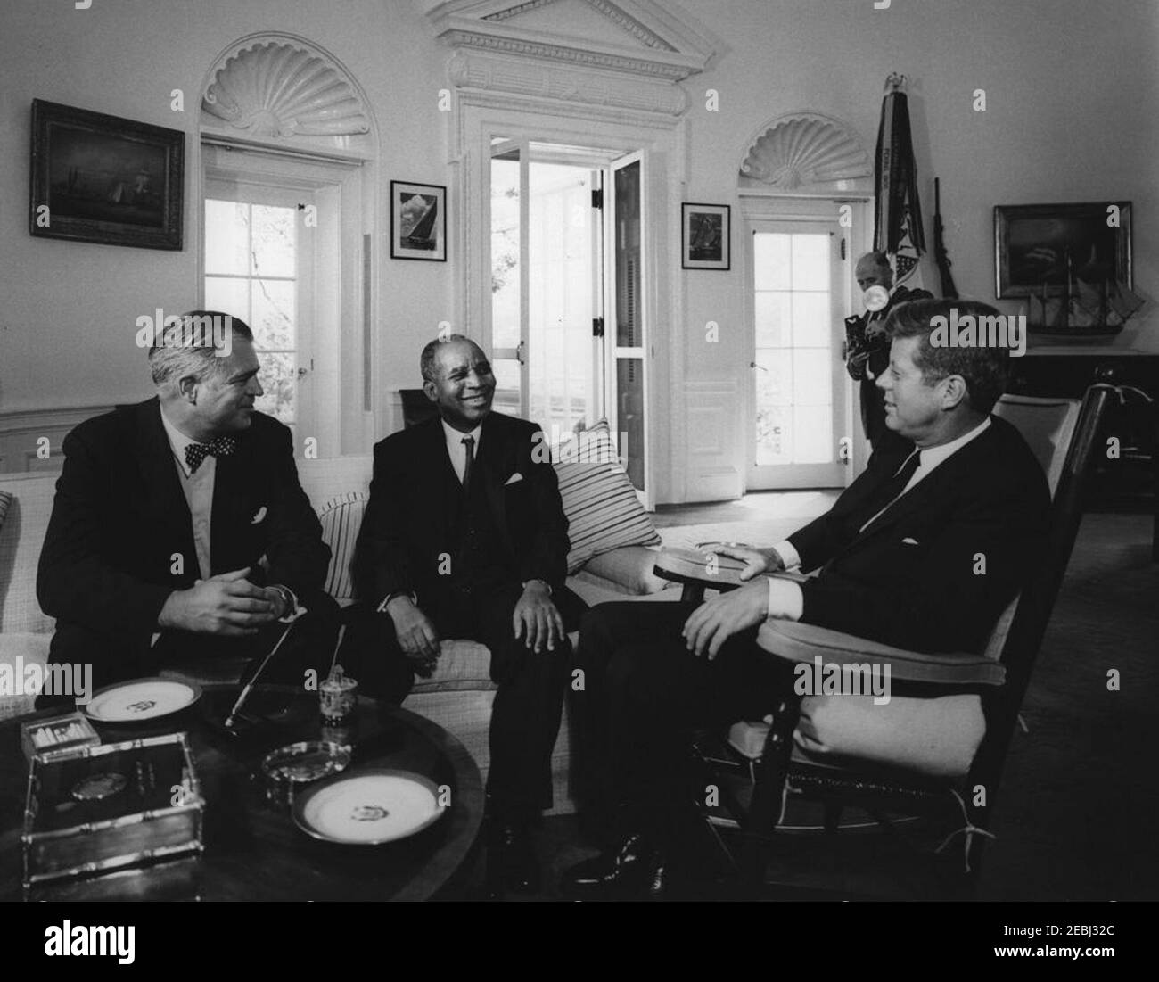 Meeting with Hastings Kamuzu Banda, Prime Minister of Nyasaland, 10:45AM. President John F. Kennedy (in rocking chair) meets with Prime Minister of Nyasaland, H. Kamuzu Banda. Assistant Secretary of State for African Affairs, G. Mennen u0022Soapyu0022 Williams, sits at far left. An unidentified photographer stands in background. Oval Office, White House, Washington, D.C. Stock Photo
