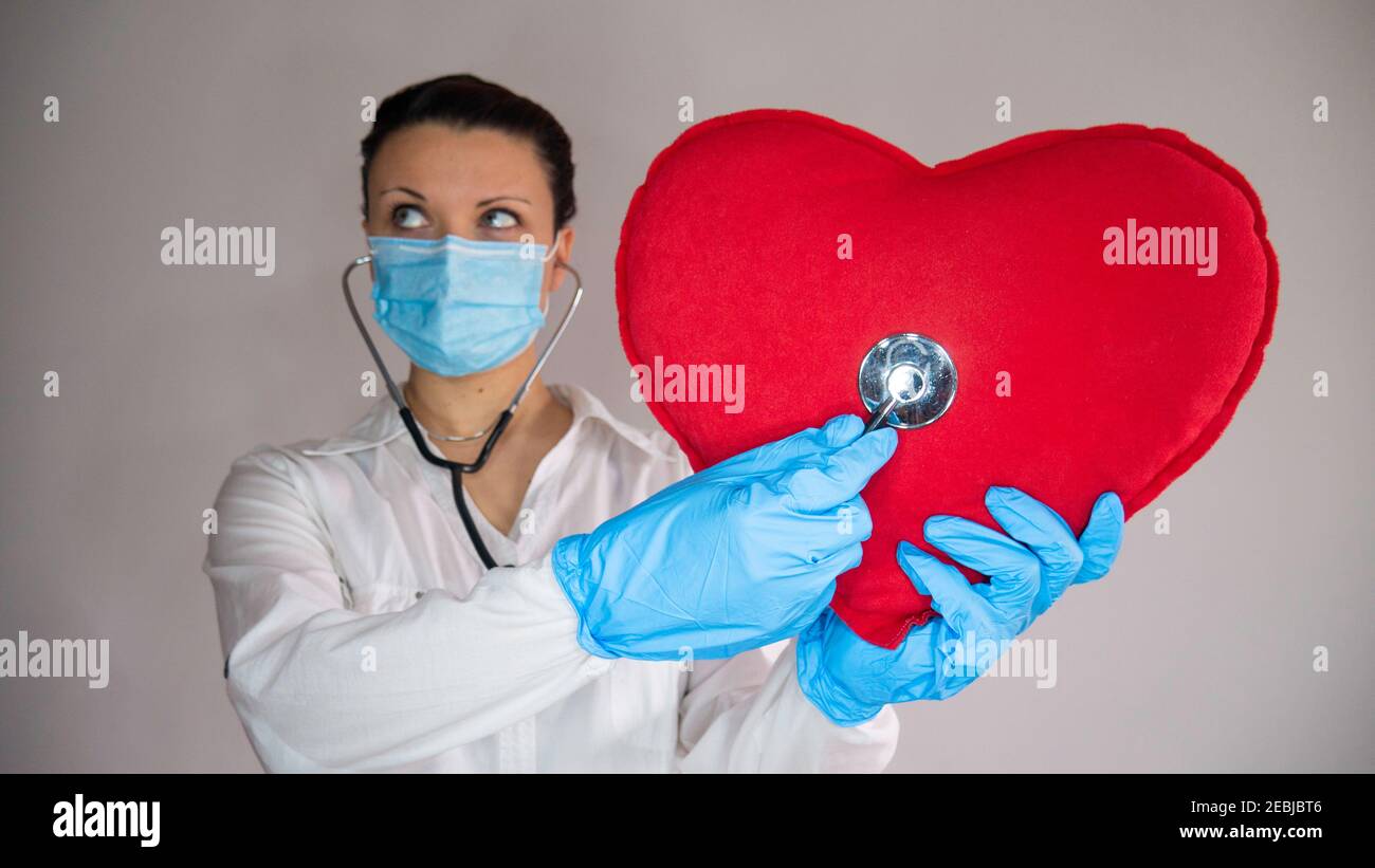 Female doctor with stethoscope listens to the big red heart Stock Photo ...