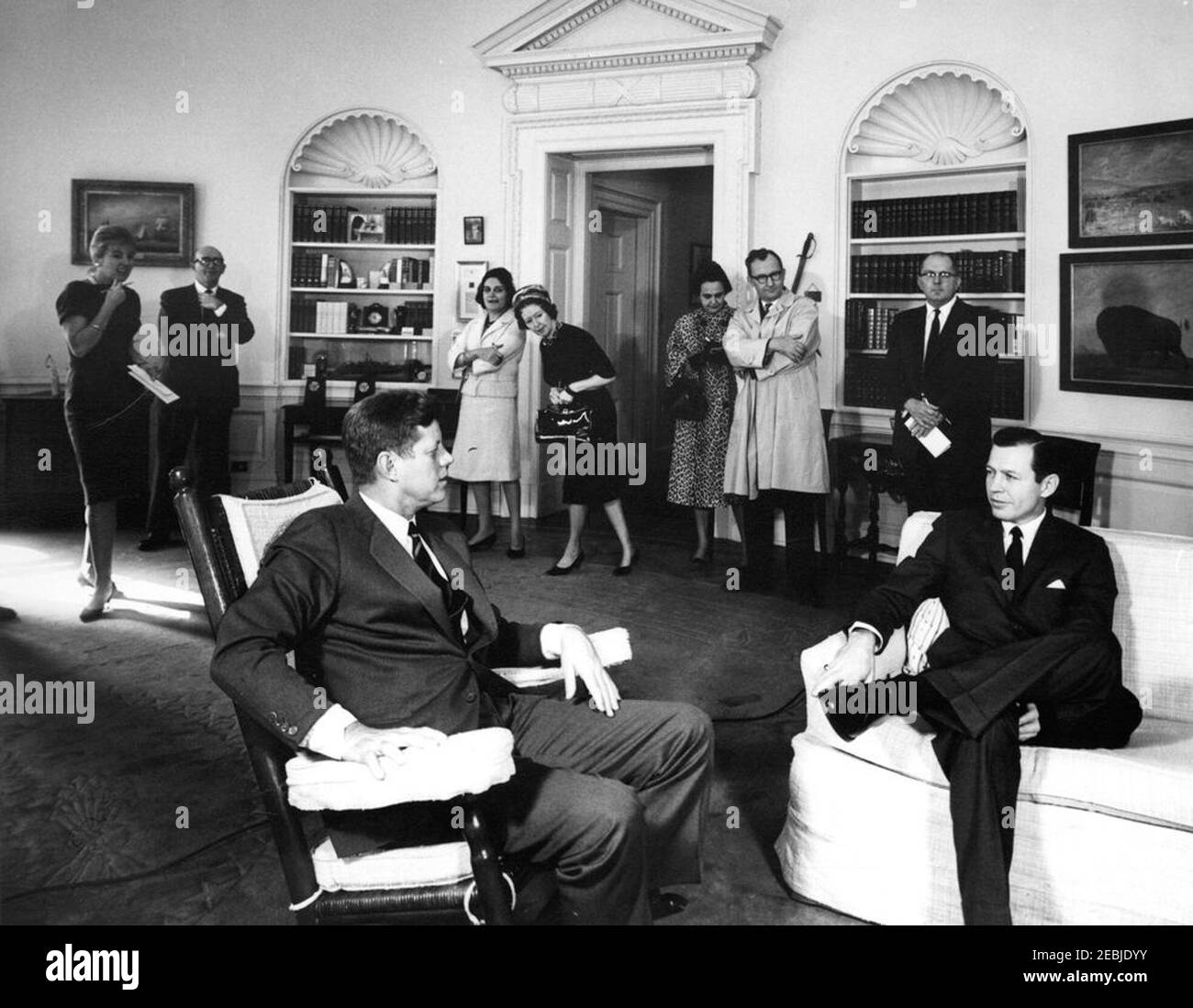 Meeting with Carl Sanders, Governor-elect of Georgia, 11:45AM. President John F. Kennedy (in rocking chair) meets with Governor-elect of Georgia, Carl Sanders. Those standing in background include: Secretary to the Assistant Press Secretary, Barbara Gamarekian; Special Assistant to the President, Dave Powers; White House correspondent for United Press International (UPI), Helen Thomas. Oval Office, White House, Washington, D.C. Stock Photo