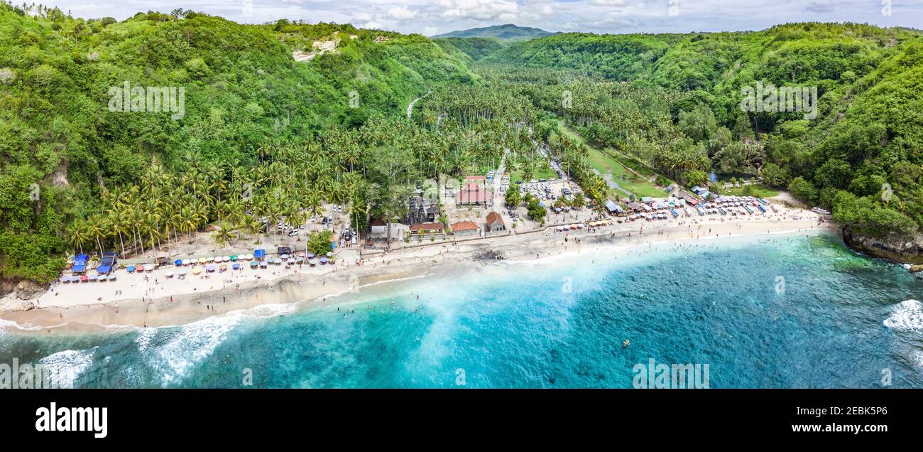 Magnificent aerial panorama of tropical beach at end of mountain valley with coconut palms, boats in blue water in Ocean gulf, unrecognized people Stock Photo