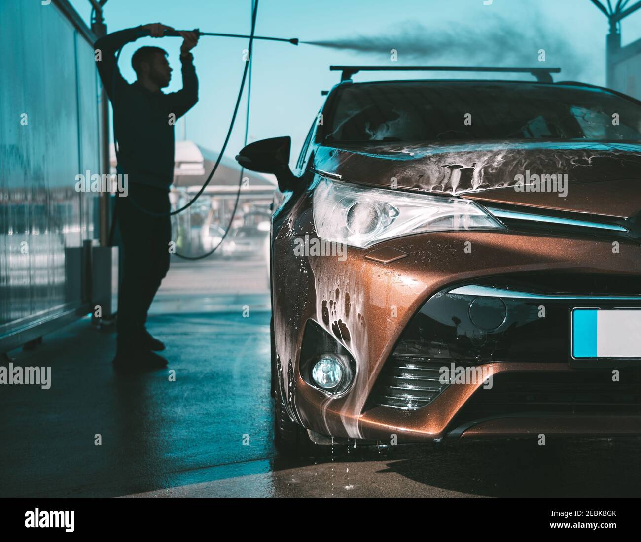 Man washing car in self serve car wash. Cleaning car using high