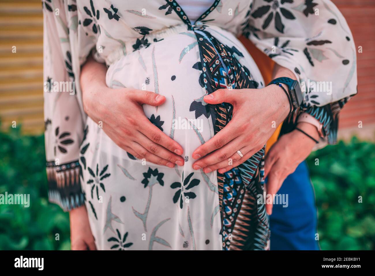 Husband hugging a pregnant woman outdoors Stock Photo