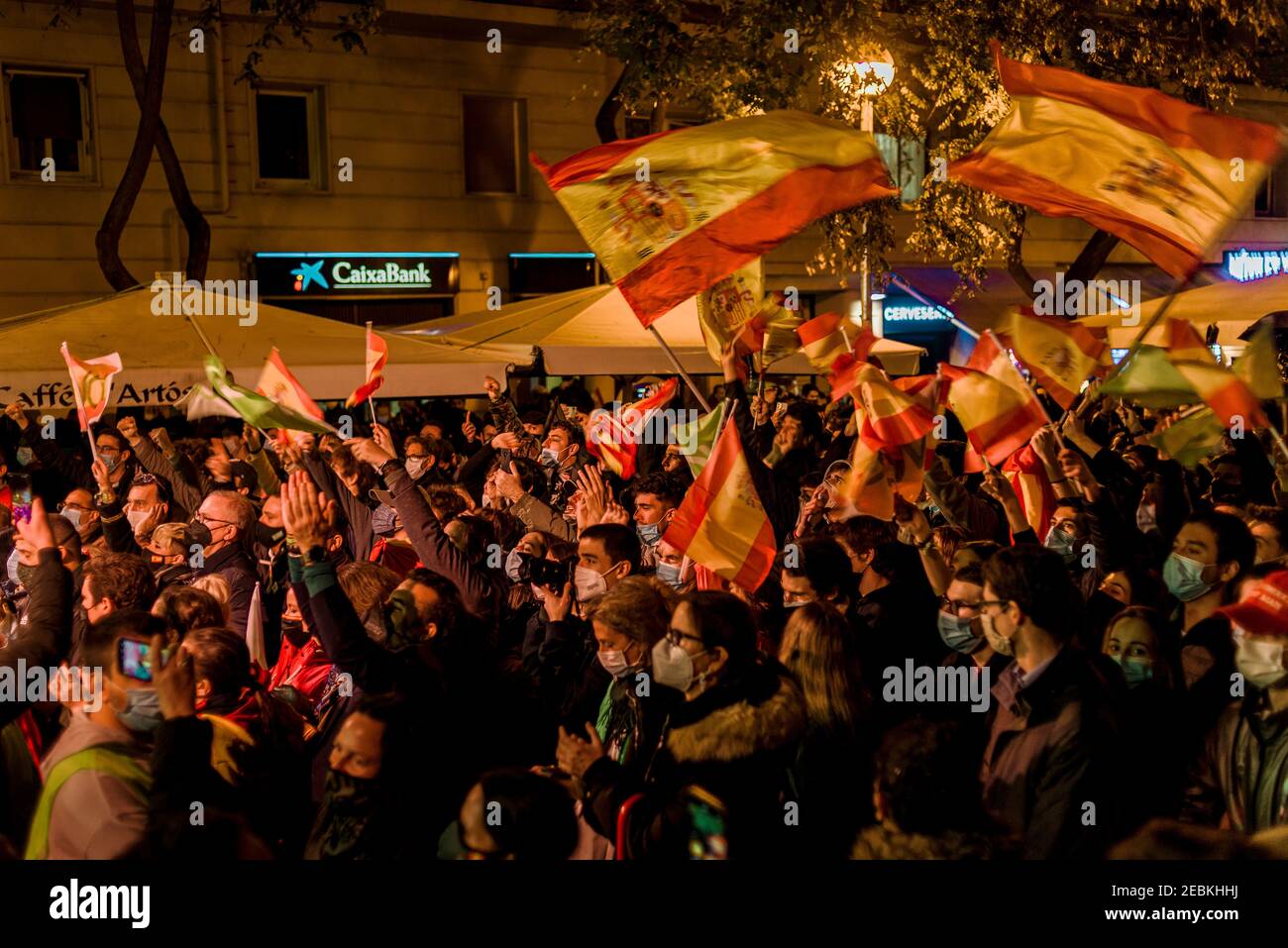 Barcelona, Spain. 12th Feb, 2021. Supporters of right-wing party VOX wearing protective face masks wave Spanish flags during the party's closing meeting of their Catalan election campaign amidst the ongoing COVID-19 pandemic Credit: Matthias Oesterle/Alamy Live News Stock Photo