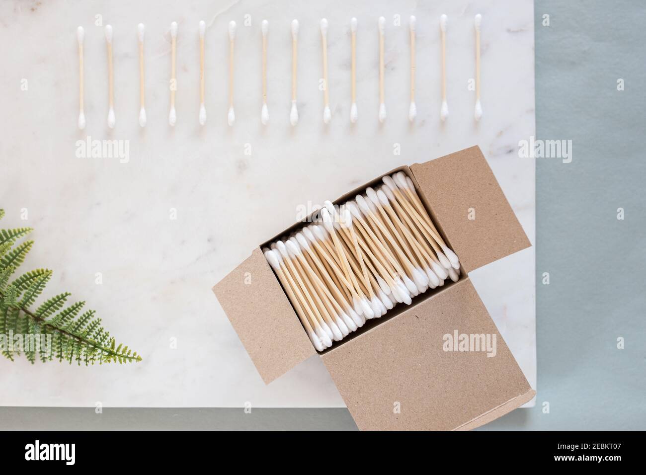 Cardboard box full of cotton swabs on a marble board with an additional