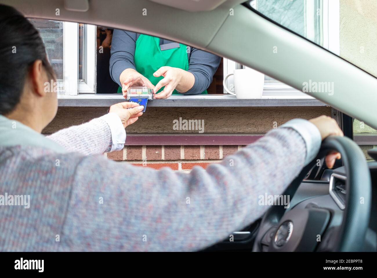 Young woman pays for service through Drive thru Stock Photo