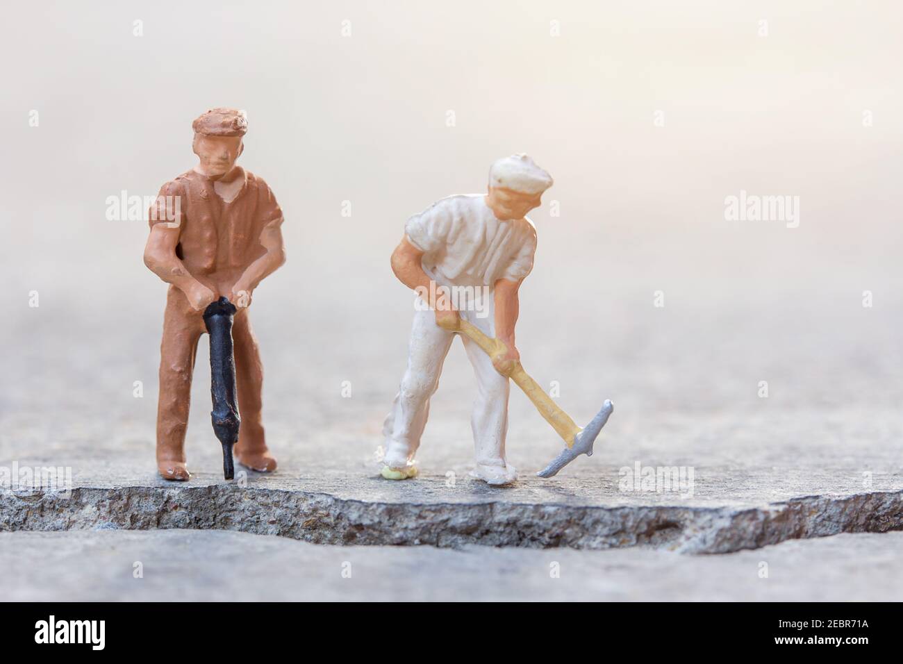 Miniature people- Figures construction worker, is working on a cracked area with blurred background and sunlight.Business and construction concept. Stock Photo