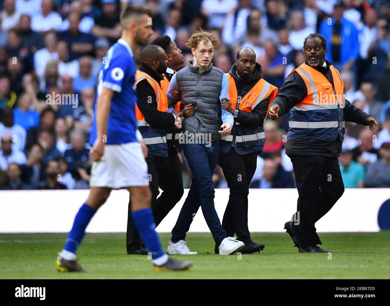 Soccer Football - Premier League - Tottenham Hotspur v Everton - Tottenham Hotspur Stadium, London, Britain - May 12, 2019  Stewards escort a pitch invader away REUTERS/Dylan Martinez  EDITORIAL USE ONLY. No use with unauthorized audio, video, data, fixture lists, club/league logos or 'live' services. Online in-match use limited to 75 images, no video emulation. No use in betting, games or single club/league/player publications.  Please contact your account representative for further details. Stock Photo