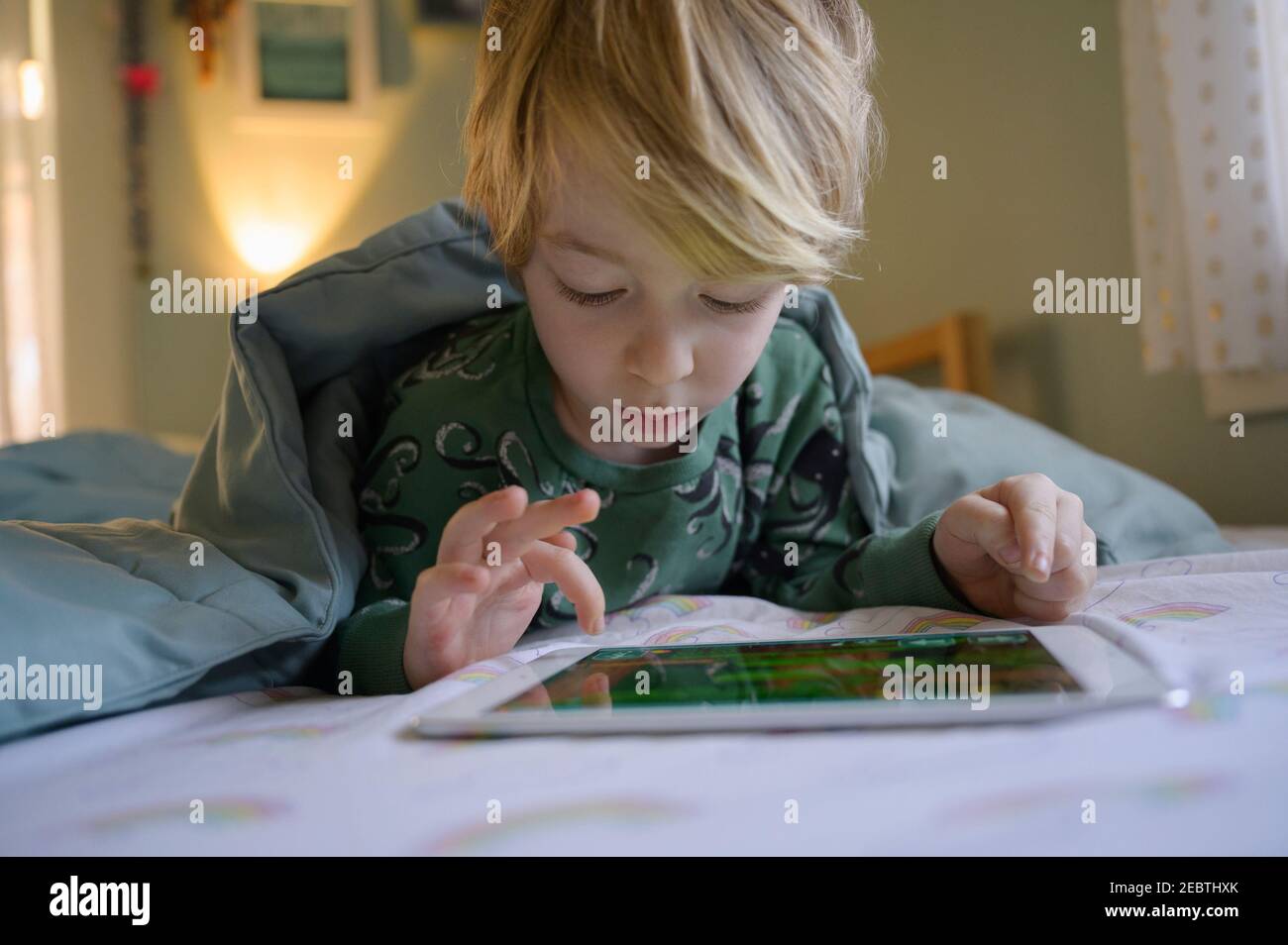Boy (6-7) on bed using digital tablet Stock Photo