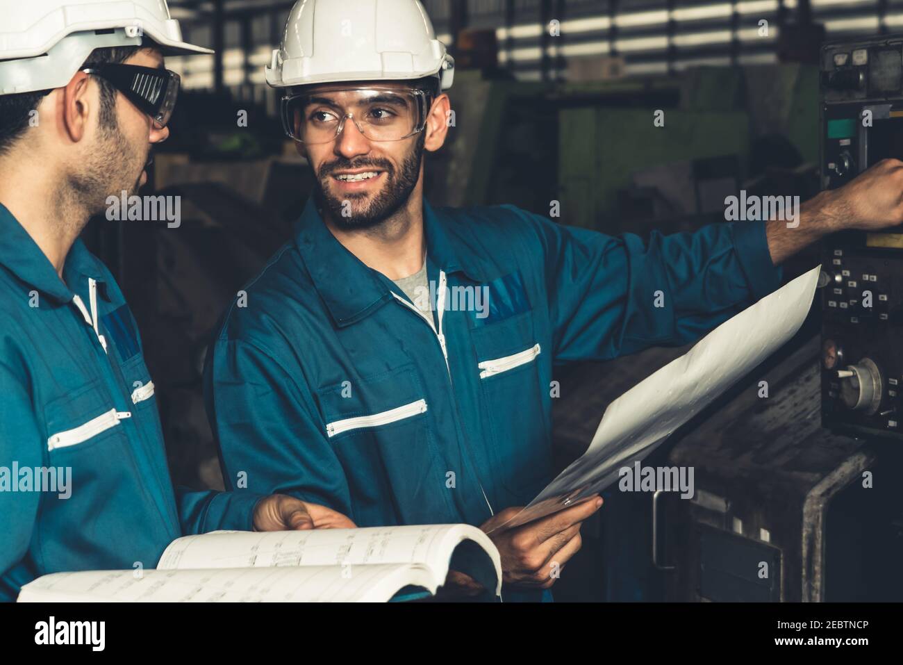 Group of skillful factory workers using machine equipment in
