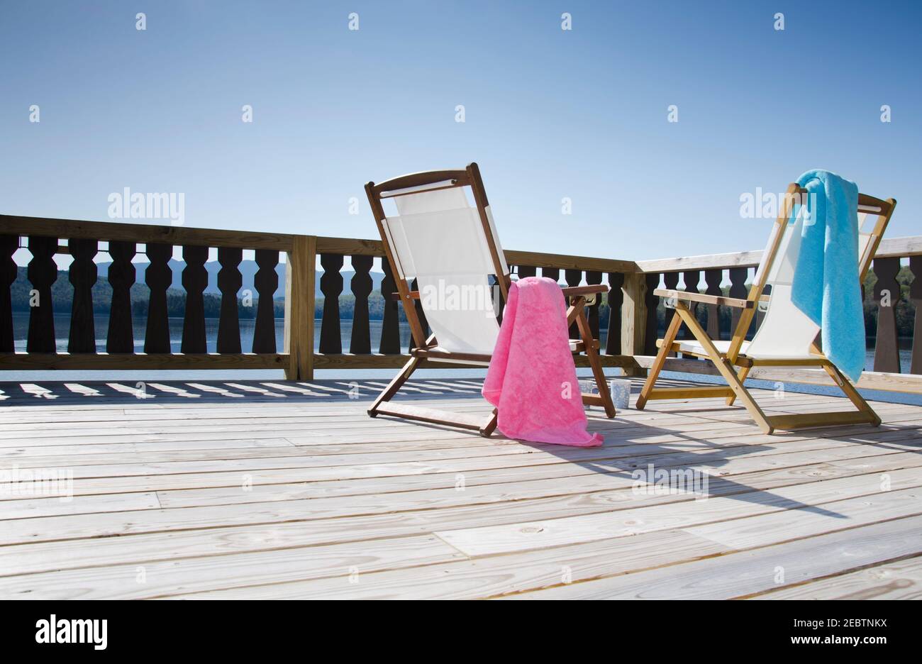 USA, New York, Lake Placid, Canvas chairs on deck overlooking lake Stock Photo