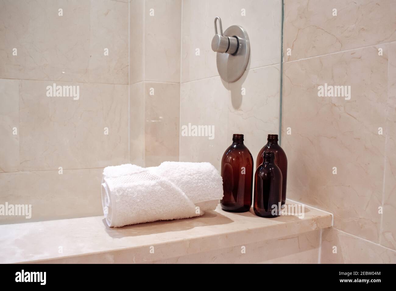 Amber glass shampoo bottles without a pump in a luxury marble hotel spa and shower. Stock Photo