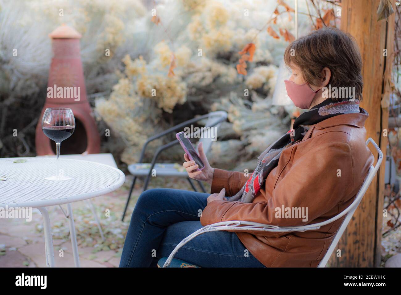 MATURE WOMAN SITTING OUTSIDE WEARING FACE MASK, SANTA FE, NM, USA Stock Photo