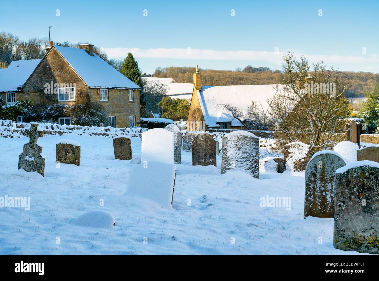 Snowshill village churchyard and cottages in the snow in January. Snowshill, Cotswolds, Gloucestershire, England Stock Photo