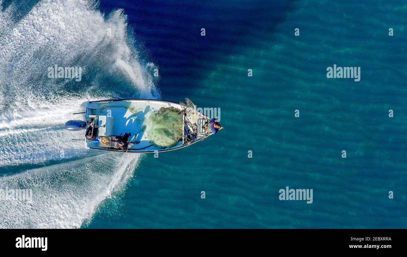 Small Fishing boat roaring across calm smooth Sea, Aerial view. Stock Photo