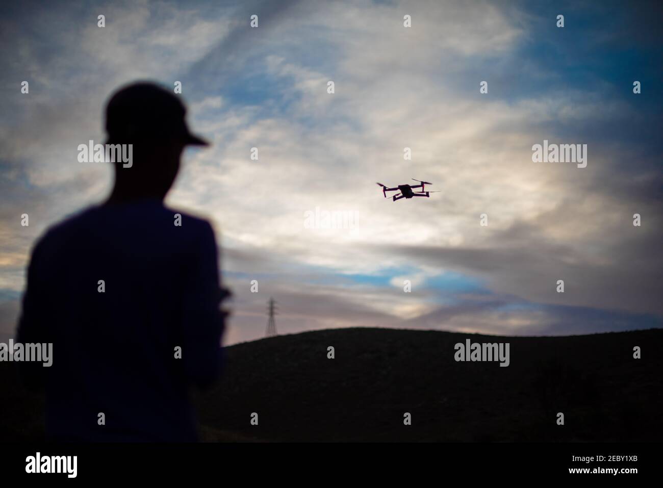 Drone seen flying during sunset with silhoutte of pilot Stock Photo